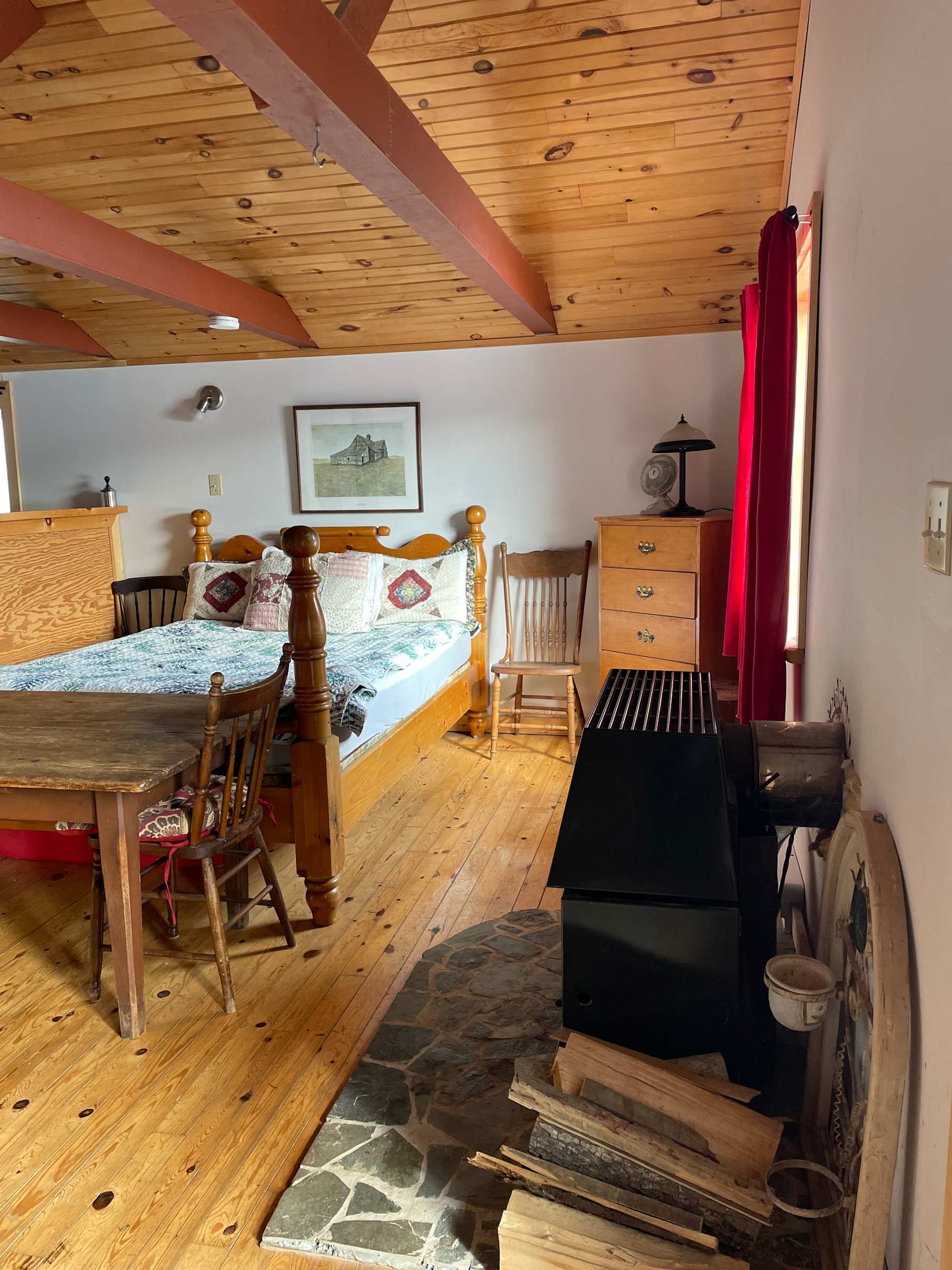 Warm cottage bedroom with a wood ceiling and wood-burning fireplace