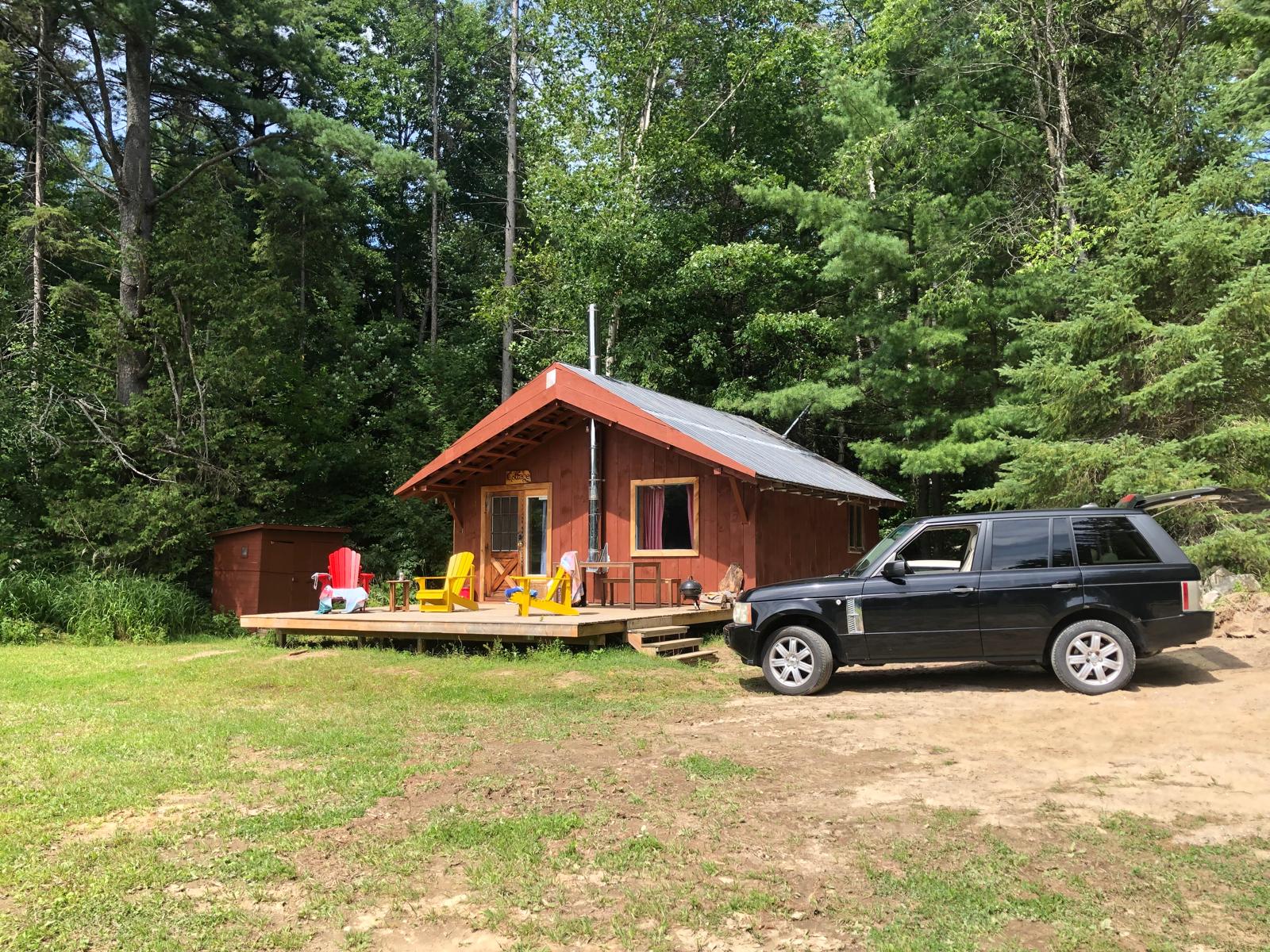 Small red cottage in a forest clearing beside the lake